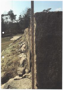 Fotografi av en steinmur eller fundament med en målebånd plassert langs kanten for å vise høyde.