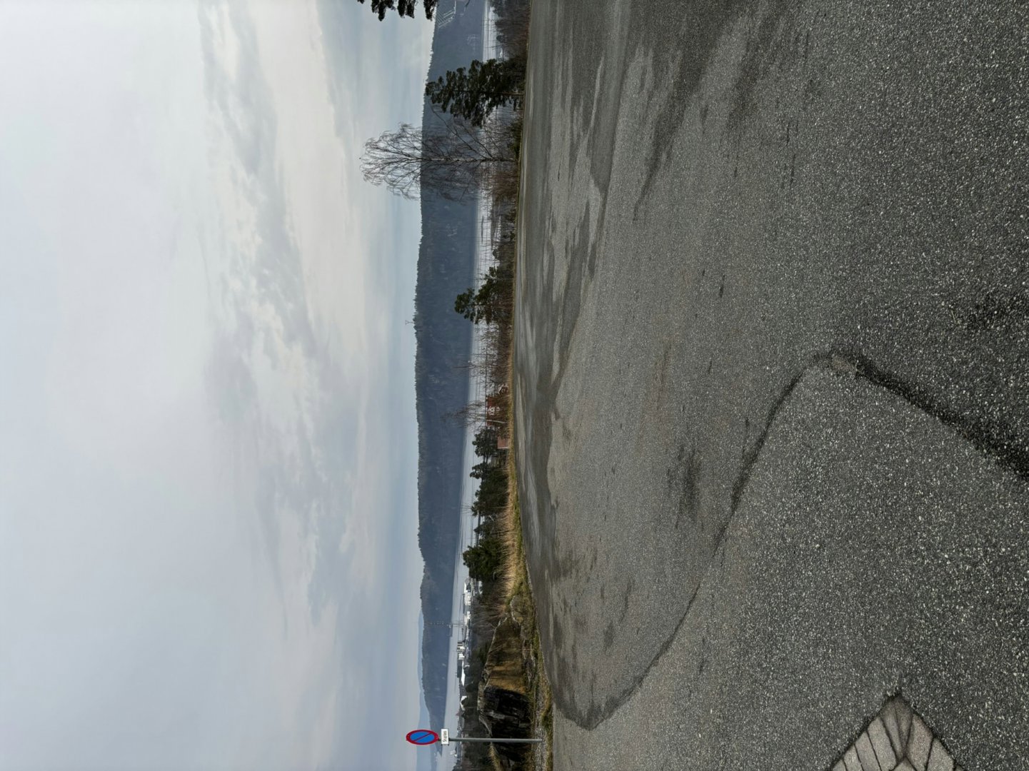 Fotografi av en vei med utsikt over vann og fjell i bakgrunnen.