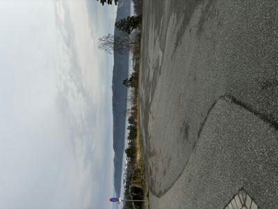 Fotografi av en vei med utsikt over vann og fjell i bakgrunnen.