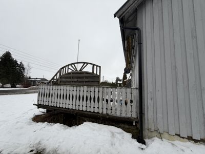 Fotografi av en bygning med hvit fasade, en uteplass med hvit balustrade og snø på bakken.