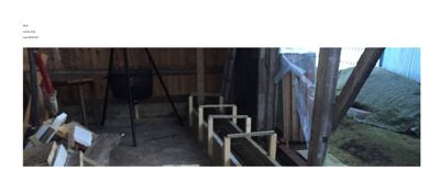 Fotografi av en uordnet, muligens under konstruksjon eller i bruk, utendørs eller halvåpen plass med trekonstruksjoner og byggematerialer.