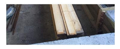 Fotografi av byggematerialer, spesifikt trevirke og armeringsstål, på en byggeplass.