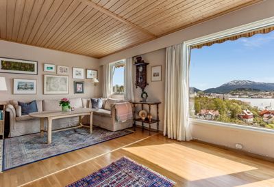 Fotografi av et innvendig stueområde med utsikt over en by og fjell.