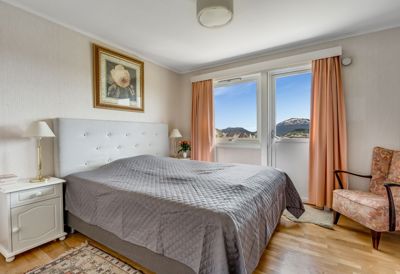 Fotografi av en soverom med senger, nattbord og utsikt til fjell.