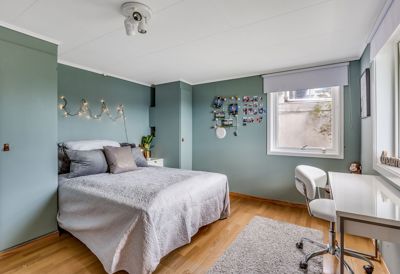 Fotografi av en innredet soverom med senger, skrivebord og vinduer.