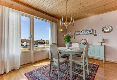 Fotografi av et spiserom med et bord, stoler, vinduer og innredning.