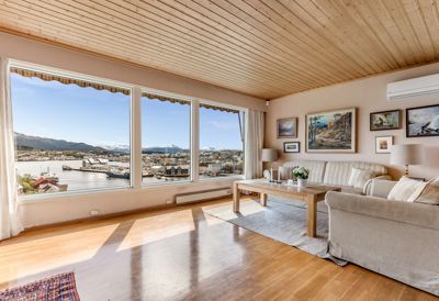 Fotografi av et innendørs stueområde med utsikt over en by og fjord.