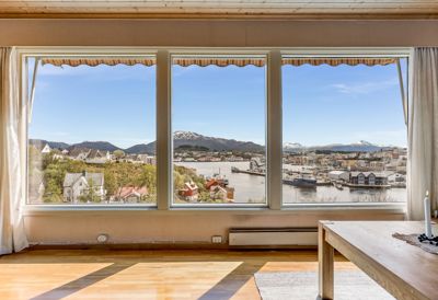 Fotografi av et rom med utsikt over en by og fjord.