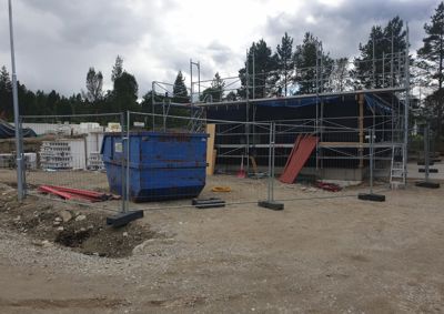 Fotografi av et bygg under oppføring med stålramme, utvendig isolasjon og utvendig heising.