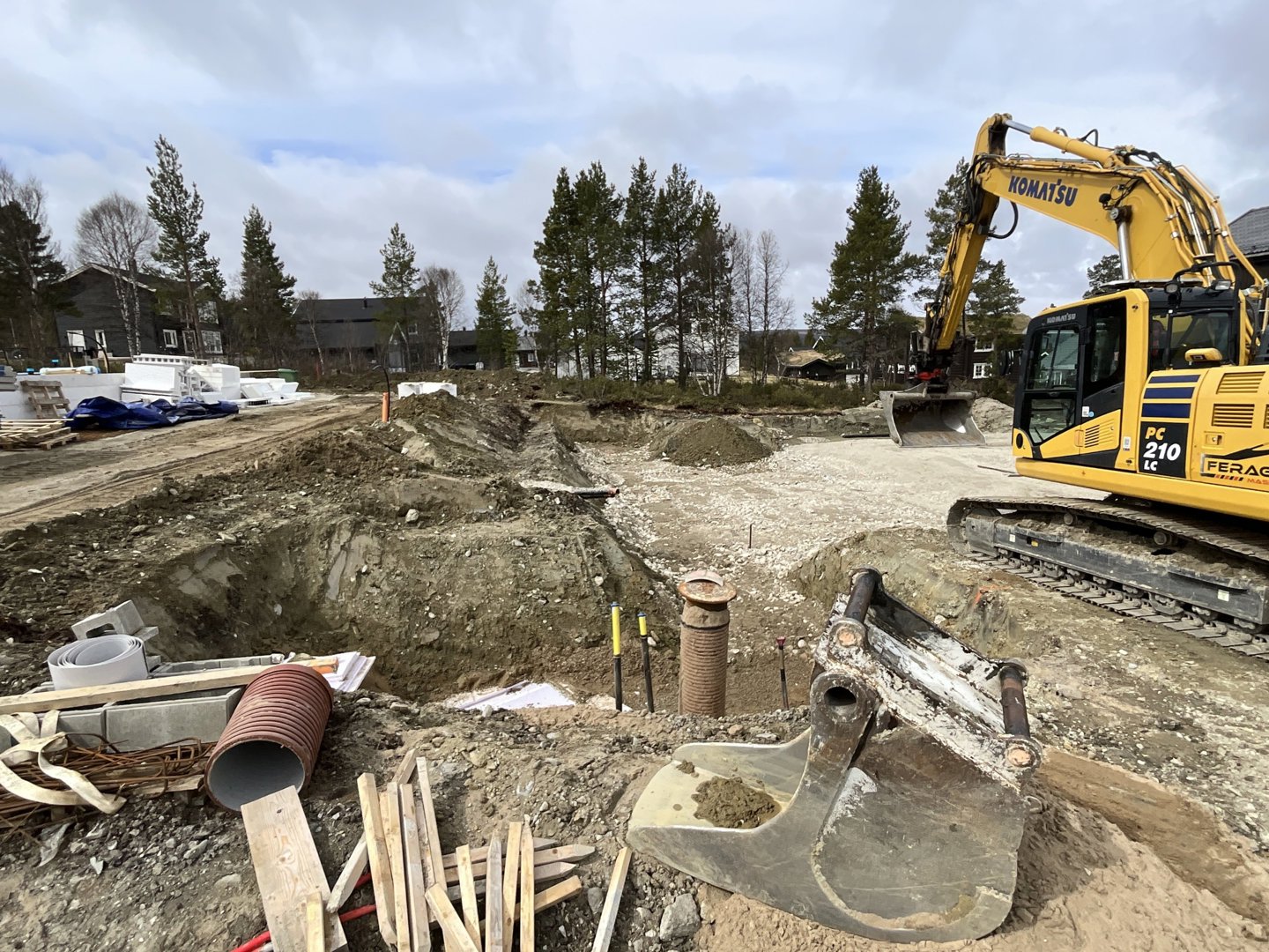 Fotografi av et byggeplass med graving, en gulegger og byggematerialer.