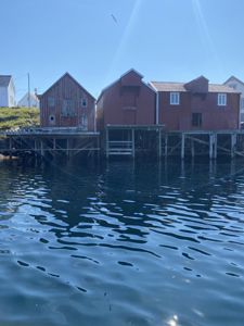 Fotografi av røde trelasthus eller fiskebuer på stolper ved vannet.