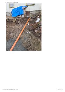 Fotografi av en ferdiggravd grøft med en oransje avløpsrør lagt i bunnen, foran en bygning. Bildet illustrerer et utført byggearbeid.