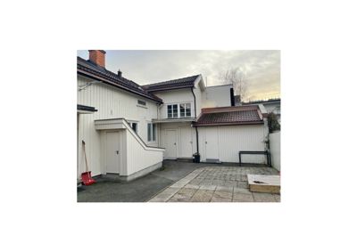 Fotografi av bakre side av en hvit, toetasjes bolig med en hage og en garasje.