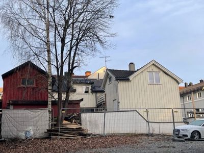 Fotografi av en bygning i en bymiljø, sannsynligvis under eller etter en byggesak, med en bil parkert foran.