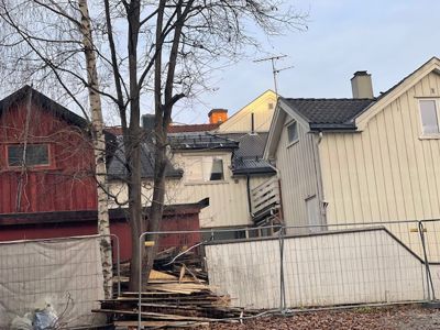 Fotografi av en byggeplass eller en tomt med flere hus i bakgrunnen, sett fra bakkenivå.