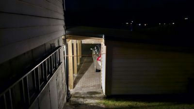 Fotografi av en bilplassering (garasje eller carport) ved siden av en bygning, tatt om natten.