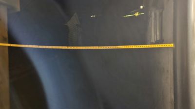 Fotografi av en gul målebånd som er spenst ut i et mørkt rom, sannsynligvis under en byggeprosess.