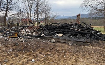 Fotografi av en bygning som har blitt brent ned, med rester av takkonstruksjon og røykpipe.