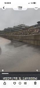 Fotografi av en byggeplass med en betongmur i forgrunnen og et bygg i bakgrunnen.
