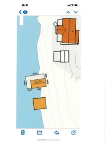 Situasjonsplan som viser tomtens form, høydeforhold (konturlinjer), vannkant, og plassering av bygninger og arealer med mål.