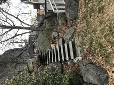 Fotografi av en trapp og en veranda som er bygd inn i en steinete bakke.