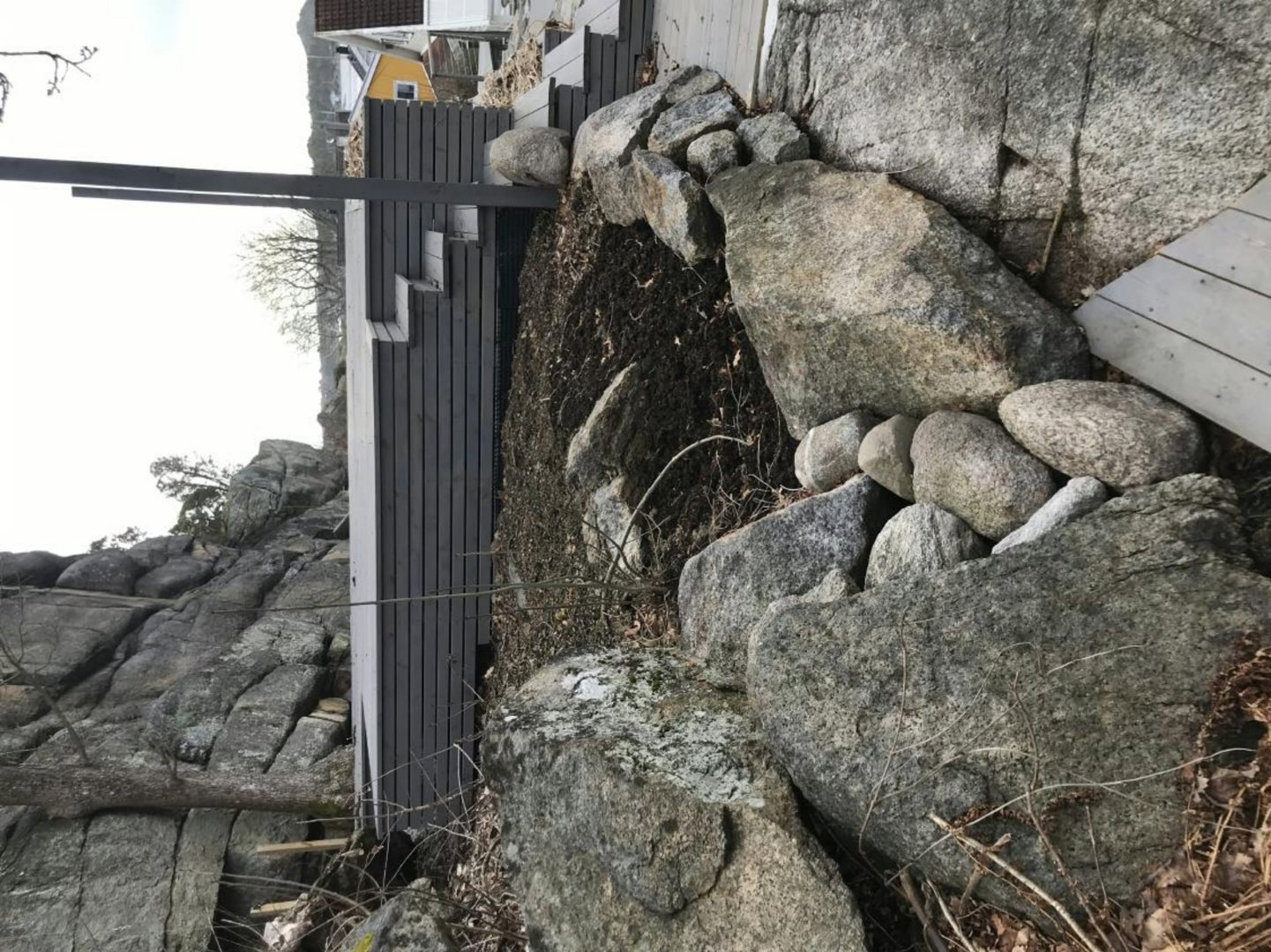 Fotografi av en bygning som er bygd inn i en steinete terreng, med en tydelig fasade og en steinmur.