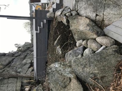 Fotografi av en bygning som er bygd inn i en steinete terreng, med en tydelig fasade og en steinmur.