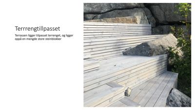 Fotografi av en terrasseløsning med tredekk og steinblokker som er tilpasset terrenget.