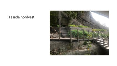 Fotografi av en fasade med trapp og hekk mot en fjellvegg