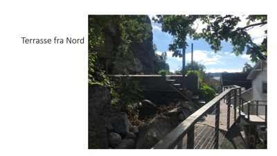 Fotografi av en terrasse og trapp sett fra nord, med natur og nabolag i bakgrunnen.