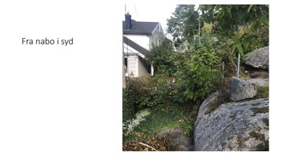 Fotografi av nabolaget sett fra sør, med en nabohus i bakgrunnen og stein i forgrunnen.