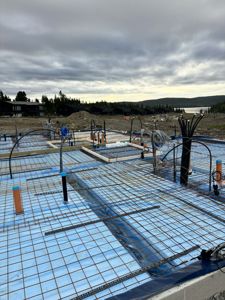 Fotografi av et fundament under bygging med armering og rørledninger.