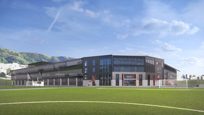 3D-visualisering av en planlagt bygning (idrettshall eller lignende) sett fra front med en fotballbane i forgrunnen.