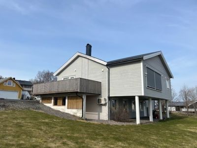 Fotografi av en eksisterende eller ferdigstilt bolig sett fra siden. Bildet viser fasaden, tak, balkong og grunnmur.