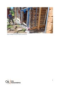 Fotografi av en person som jobber med muring på en tømmerhytte under bygging.