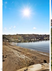 Fotografi av et kystlandskap med strand, vann og sol.
