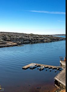 Fotografi av en havneområde med båtplasser, kai og kystlinje.