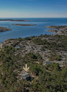 Luftfoto av et hus i et kystlandskap med en pil som peker på det aktuelle bygget.