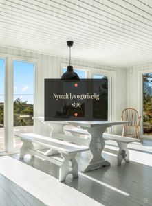 Fotografi av en innendørs stue med hvite panelvegger, gulv og møbler.