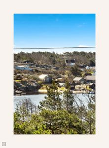 Fotografi av et kystlandskap med hus, vann og vegetasjon.