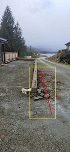 Fotografi av en grusvei med en betongmur og en markert linje (rød og gul) som indikerer en planlagt eller eksisterende grense.