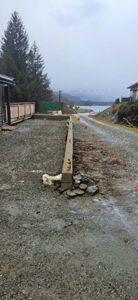 Fotografi av en byggeplass med en ny mur som er under oppføring, en grusvei og en del av en eksisterende bygning i bakgrunnen.