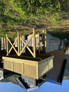 Fotografi av en ferdig eller underveis bygget utvidelse med en stor terrasse på stolper.