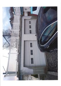 Fotografi av fasaden på en bygning, sannsynligvis en garasje eller kjeller, med to store dører og en balustrade til venstre.