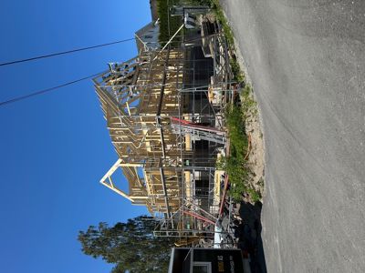 Fotografi av en bygning under oppføring med synlig tømmerkonstruksjon og stålramme.